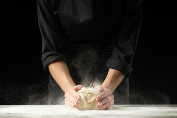 Bakery. Man preparing the bread, Easter cake, Easter bread or cross buns on a wooden table in the bakery close up. Cook preparing bread dough.