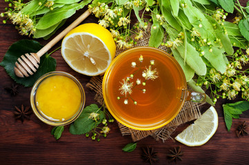 Herbal tea with lime flowers in a glass cup on a dark wooden surface. Useful and tasty drink. Folk...
