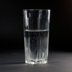 Transparent glass of water on a dark gray background