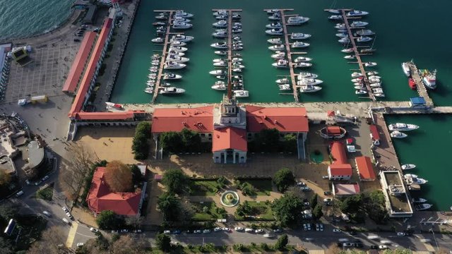 Commercial sea port of Sochi. Aerial photography with quadrocopter. Hyperlapse. Yachts, sea, people, cars in motion. Clouds are flying over the building.The landmark of the city of Sochi.