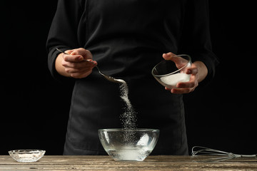 Baker preparing yeast dough, on a dark background. Bakery concept and dough preparation