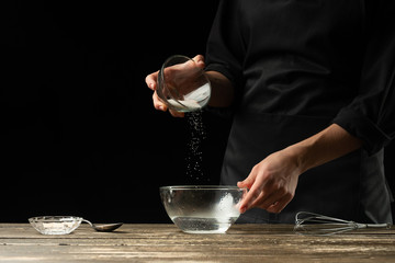 Baker preparing yeast dough, on a dark background. Bakery concept and dough preparation