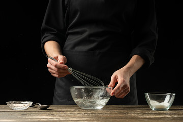 Baker preparing yeast dough, on a dark background. Bakery concept and dough preparation