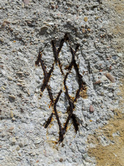 Iron rusted rhomboid fitting in a breakaway concrete wall maiden with pebble using