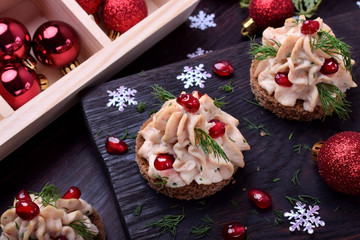 Canape shaped as a Christmas tree with pate garnished with pomegranate and dill surrounded by Christmas decorations