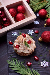 Obraz na płótnie Canvas Canape shaped as a Christmas tree with pate garnished with pomegranate and dill surrounded by Christmas decorations