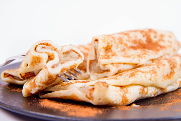 Pancakes stuffed with braised apples sprinkled with cinnamon eaten with a fork