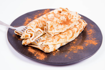 Pancakes stuffed with braised apples sprinkled with cinnamon eaten with a fork