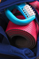 Pink yoga mat, massager in a blue gym bag.