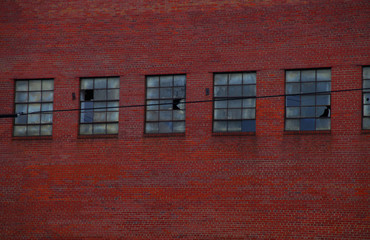 Industrial red brick wall with broken windows