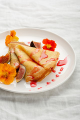 Sweet crepes with sauce on white plate