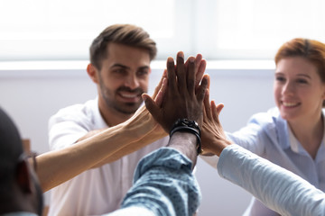 Happy diverse businesspeople giving high five, close up focus on people hands. Friendly multiracial...