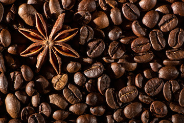 Coffee beans background with different spices: anise stars and cinnamon sticks. Christmas concept.
