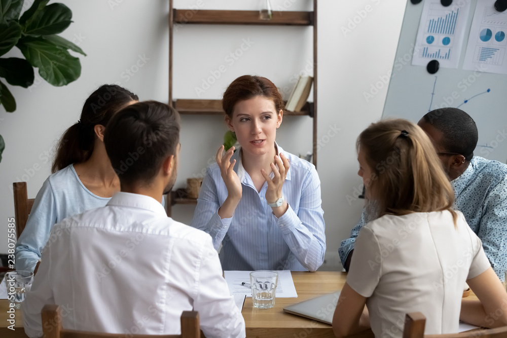 Wall mural five diverse people brainstorming sitting around desk in briefing at boardroom. attentive multiracia