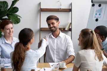 Successful businesspeople gathered together in office boardroom for negotiate and discuss new project greeting shaking hands. Company executive manager welcoming newcomer new worker female handshaking