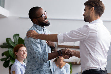 Diverse people gathered in meeting executive manager shake hands with black employee impressed by...