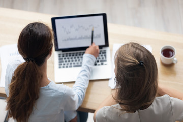 Top above rear view businesswoman sitting together at office desk working using computer business...