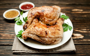 Chicken legs in a plate with mustard and ketchup on a wooden background.