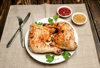 Chicken legs in a plate with mustard and ketchup on a wooden background.