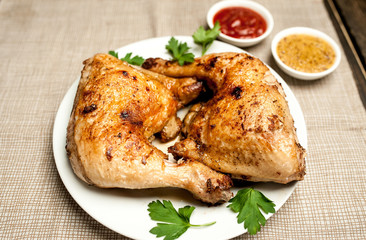 Chicken legs in a plate with mustard and ketchup on a wooden background.