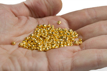 A bunch of gold pellets on the palm. Isolated on white background.