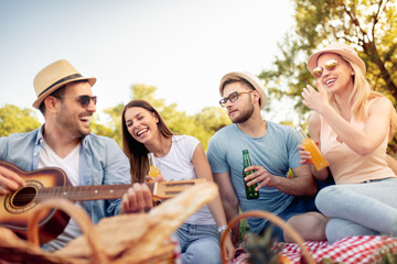 Group of happy friends having fun outdoors with guitar