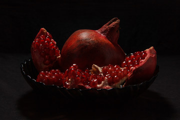 Appetizing red pomegranate in a plate on a dark background