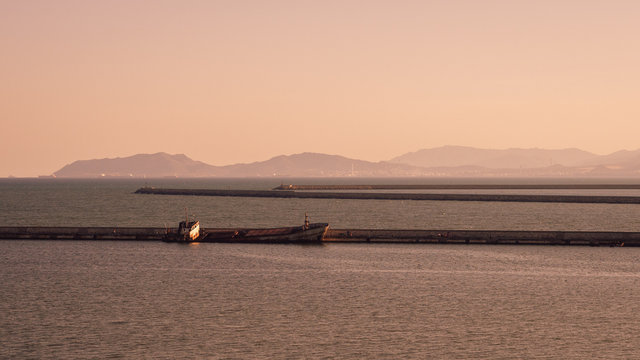 Semi-sunken ship abandoned along a jetty.