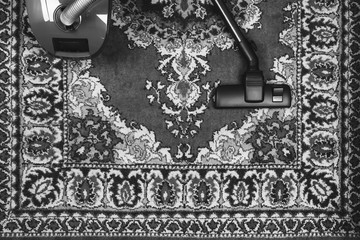 electric vacuum cleaner on the background of an old carpet, top view of flat lay, black and white photo