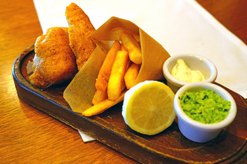 A plate of traditional beer-battered fish and chips with mashed green peas