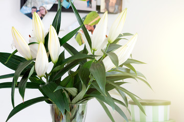 Bouquet of lilies. Photos of a couple in love from trips on the wall. Toned with sunlight.