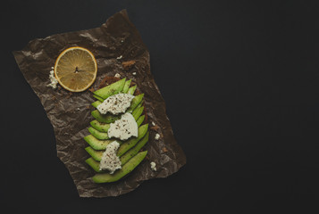 Fresh delicious avocado toast with white cheese on black background with copyspace.
