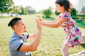 Fototapeta premium Dad and daughter summer outdoor activity. Loving father adore his lovely playful baby. Parent and child have fun in park. Carefree childhood. Happy family lifestyle portrait. Cheerful girl clapping