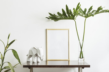 The stylish interior with mock up poster frame, leafs and elephant sculpture. The minimalizm concept of space. 