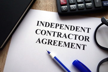 Independent contractor agreement, pen, glasses and   calculator on desk