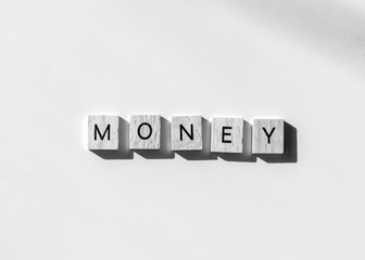 Money spelled in letter tiles, black and white flat lay