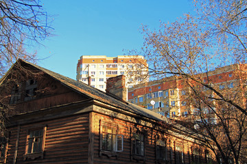 Old country house on the background of modern high-rise buildings. Cityscape. The concept of absorption by the village