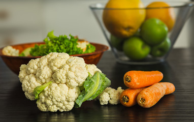Cauliflower with other vegetables on the table (carrots,onions,lettuce).