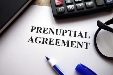 Prenuptial agreement, pen, glasses and calculator on desk