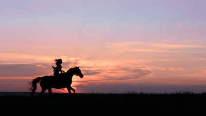 Fototapeta na wymiar Galloping horse with female rider on beautiful colorful sunset background. Romantic equine and female silhouette on horse hiking with red rising sun on horizon
