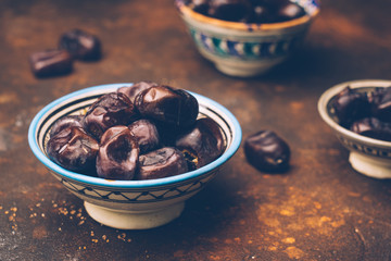 Dried dates in an oriental ceramic bowl on a dark background. Ramadan snacks