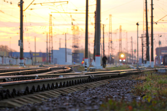 Railway tracks and riding train at sunrise. Man going to work in the morning. Railway background, station.  Landscape