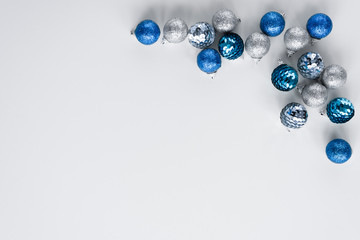 Scattered silver and blue little baubles arranged as a frame on white background. Minimalistic greeting card for Christmas. Copy space for wishes.