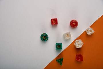 Unusual dice for board games on a two-tone white and orange background, table. Accessories, pebbles, cubes for playing the famous board game "Dungeons and Dragons".