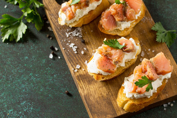 Antipasti snacks for Wine. Brushetta with Soft Cheese and Salmon on a rustic wooden board on a stone table. Copy space. Copy space.