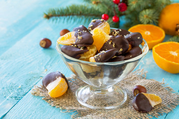 Slices of Tangerines in Chocolate. Dessert Tangerines on a blue on a wooden table. Copy space.