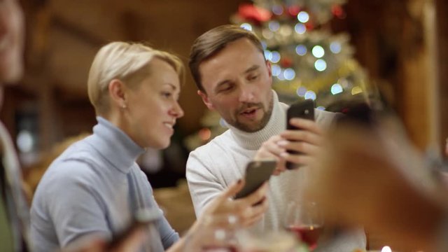 Loving husband sharing memes with his wife by Christmas table