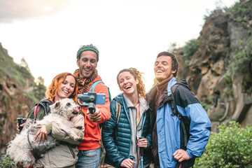 Happy friends recording video with mobile smartphone camera on mountain at sunset - Young people trekking and having fun with new technology trends - Sport, hiking, Tech and social media concept