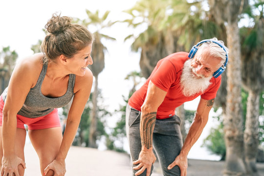 Fit couple of friends having a break after a fast race next the beach at sunset - Sporty people workout outdoor - Fitness, wellness, sport, jogging and health lifestyle concept