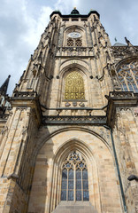 Fototapeta na wymiar The Cathedral of Saint Vitus (1344) in Prague, Czech Republic, side view architectural detail, with the clock tower and arched windows covered in gold